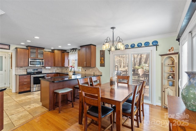 dining room with an inviting chandelier, light wood-style flooring, crown molding, and a wealth of natural light