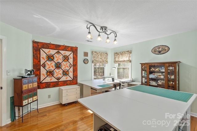 office area with light wood-style flooring, baseboards, and an inviting chandelier