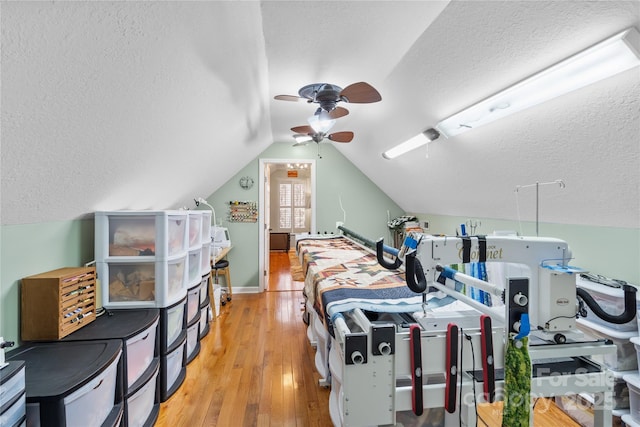 bedroom featuring ceiling fan, a textured ceiling, light wood-style flooring, and vaulted ceiling