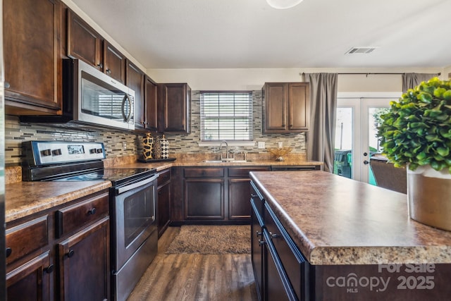 kitchen with visible vents, a sink, stainless steel appliances, dark brown cabinets, and tasteful backsplash