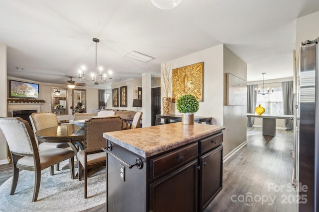 kitchen with dark wood finished floors, freestanding refrigerator, a fireplace, light countertops, and hanging light fixtures