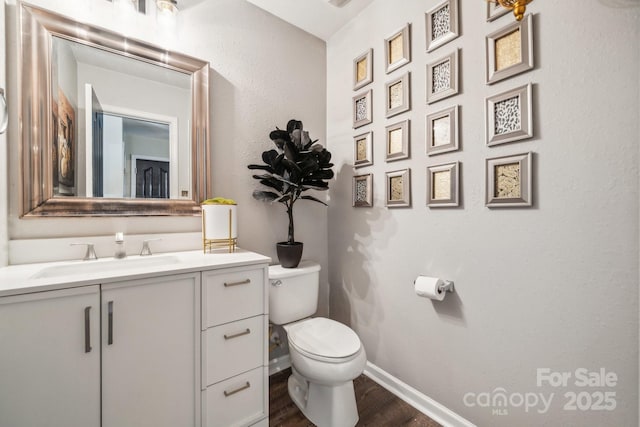 bathroom with baseboards, toilet, wood finished floors, and vanity