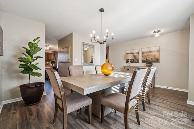 dining room featuring a chandelier, baseboards, and wood finished floors