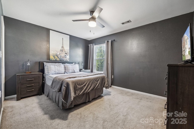 bedroom with visible vents, light carpet, a ceiling fan, baseboards, and a textured wall