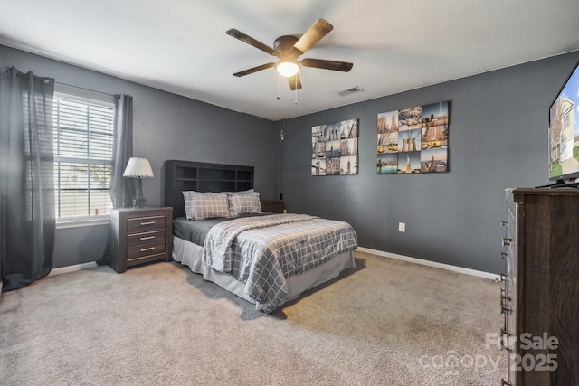 bedroom with visible vents, light colored carpet, baseboards, and ceiling fan