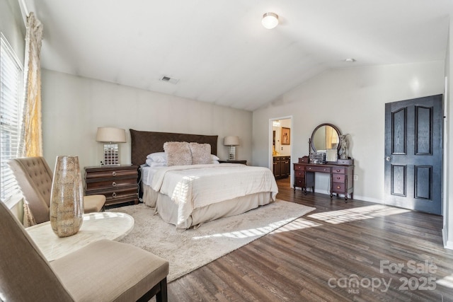 bedroom featuring visible vents, connected bathroom, lofted ceiling, and wood finished floors