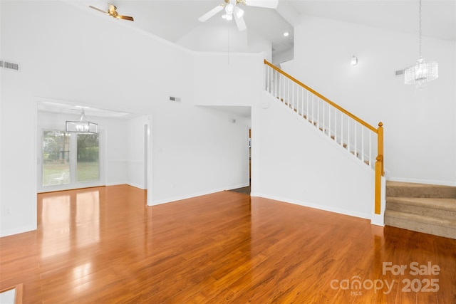 unfurnished living room featuring wood finished floors, stairway, ceiling fan with notable chandelier, and visible vents