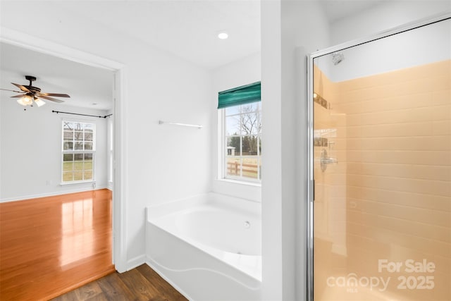 full bath featuring baseboards, wood finished floors, a garden tub, and a stall shower