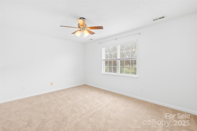 carpeted empty room featuring visible vents, baseboards, and a ceiling fan