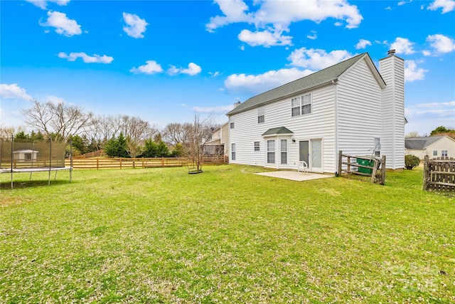 rear view of house with a patio area, a lawn, a trampoline, and fence