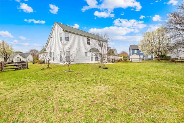 rear view of property featuring a yard and fence