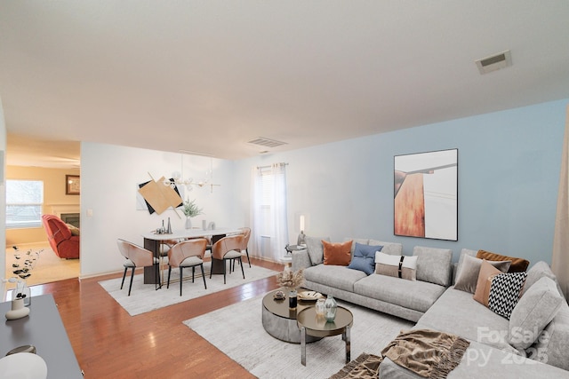 living area featuring wood finished floors, visible vents, and a chandelier