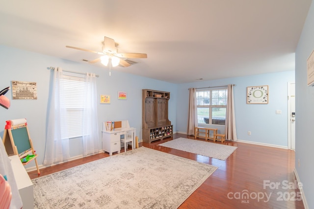 playroom with a ceiling fan, wood finished floors, and baseboards