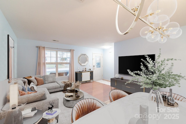 living room with a chandelier, visible vents, and wood finished floors