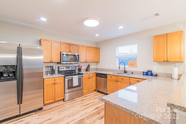 kitchen featuring light brown cabinets, visible vents, light wood finished floors, a sink, and stainless steel appliances