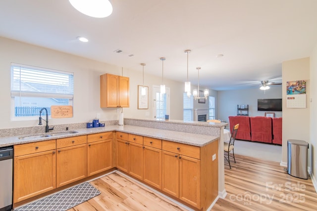 kitchen with a ceiling fan, a peninsula, light wood-style flooring, a sink, and stainless steel dishwasher