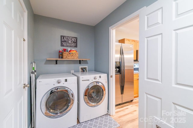 clothes washing area with independent washer and dryer, light wood-style flooring, and laundry area