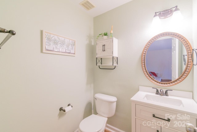 bathroom with vanity, toilet, baseboards, and visible vents