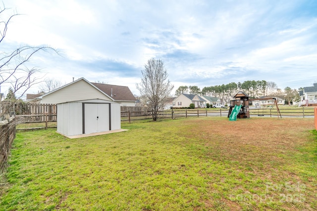 view of yard featuring an outbuilding, a playground, a storage unit, and a fenced backyard