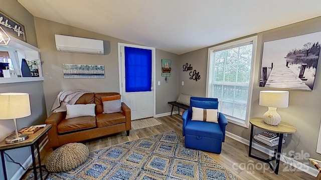 sitting room featuring baseboards, wood finished floors, a wall unit AC, and vaulted ceiling