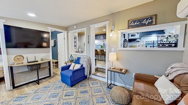 living room featuring wood finished floors, baseboards, and a wall mounted air conditioner