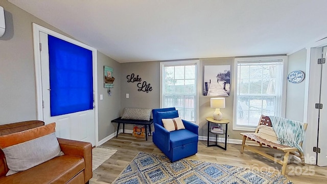 sitting room with light wood-type flooring, baseboards, and a healthy amount of sunlight