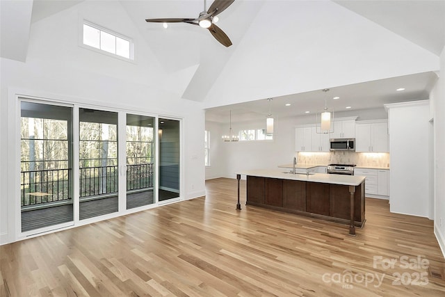 kitchen with light wood-type flooring, a sink, a kitchen breakfast bar, appliances with stainless steel finishes, and light countertops