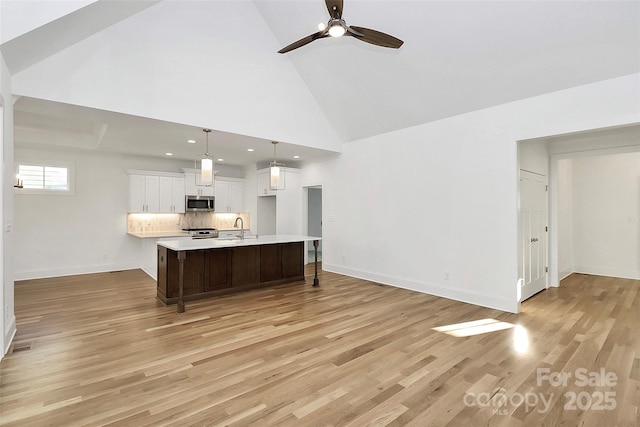 kitchen featuring a sink, light countertops, white cabinets, light wood-style floors, and stainless steel microwave