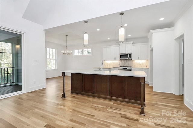 kitchen with light wood-style flooring, a sink, stainless steel appliances, light countertops, and white cabinets