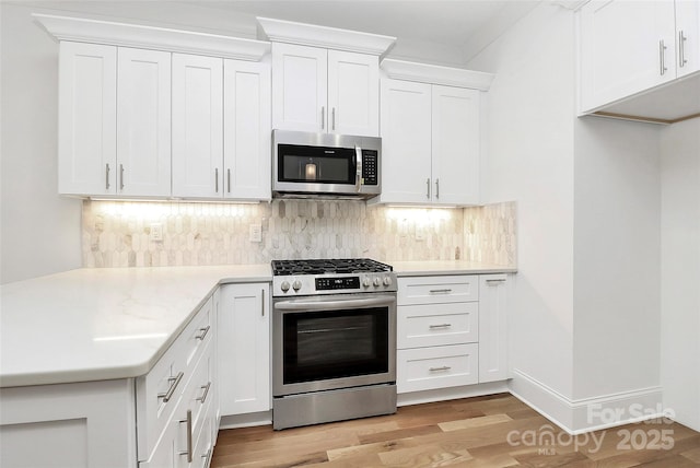 kitchen featuring light wood finished floors, light countertops, decorative backsplash, white cabinets, and stainless steel appliances