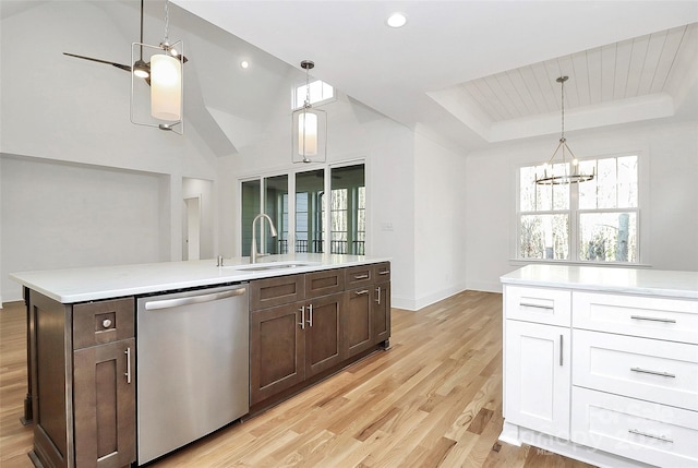 kitchen featuring dark brown cabinetry, dishwasher, light countertops, a tray ceiling, and a sink