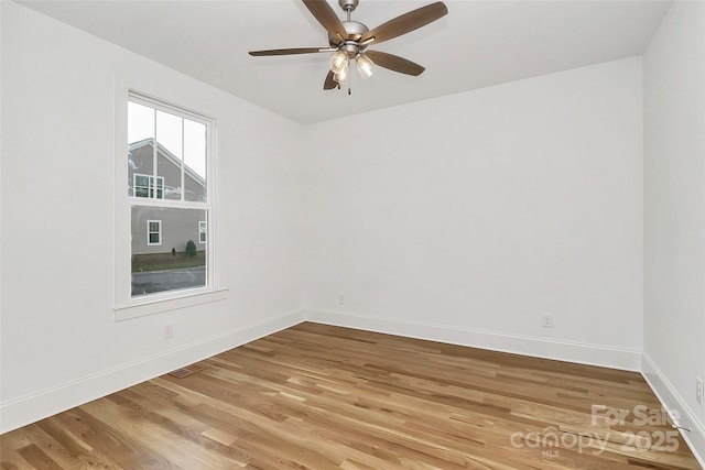 spare room featuring light wood-type flooring, baseboards, and ceiling fan