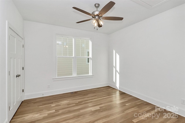 empty room with light wood-style flooring, a ceiling fan, and baseboards