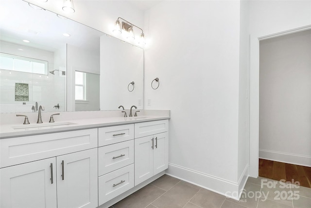 bathroom with tile patterned floors, a shower stall, baseboards, and a sink