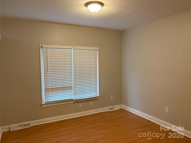 unfurnished room with visible vents, baseboards, and wood finished floors