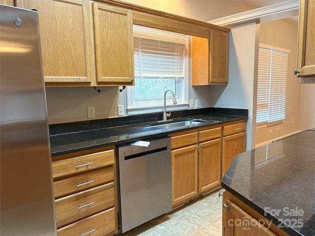 kitchen featuring stainless steel appliances, dark stone counters, and a sink