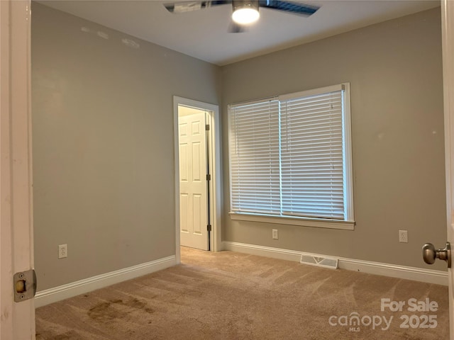 empty room with ceiling fan, carpet, visible vents, and baseboards