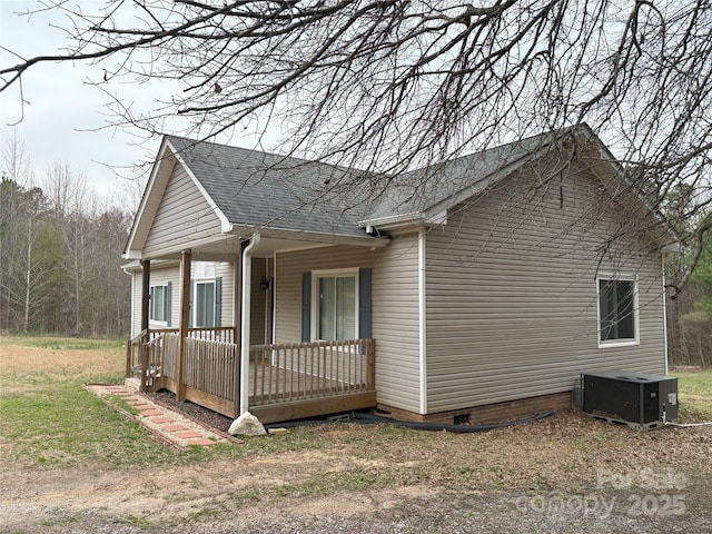 view of property exterior featuring crawl space, cooling unit, covered porch, and a shingled roof