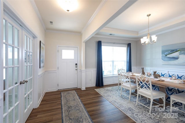 entrance foyer featuring a wainscoted wall, visible vents, an inviting chandelier, dark wood-style flooring, and ornamental molding