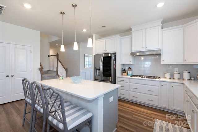 kitchen featuring backsplash, a kitchen island, under cabinet range hood, a breakfast bar area, and appliances with stainless steel finishes