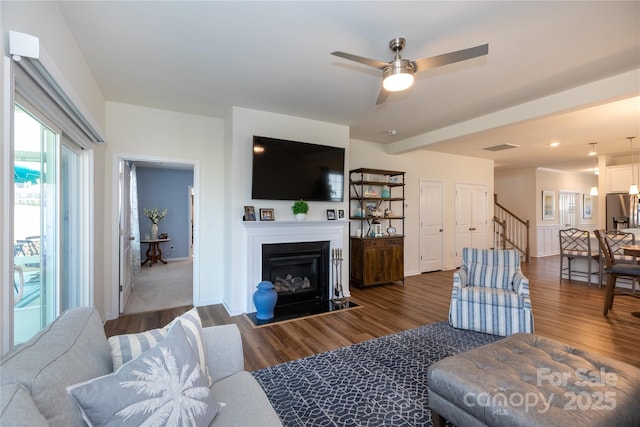 living room featuring stairway, visible vents, wood finished floors, and a fireplace