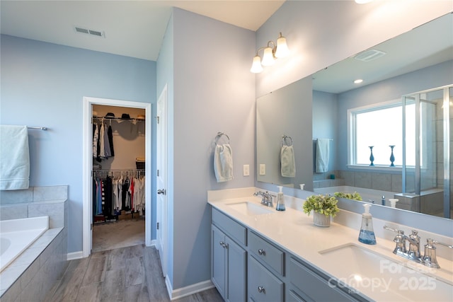 bathroom with a sink, visible vents, a bath, and double vanity