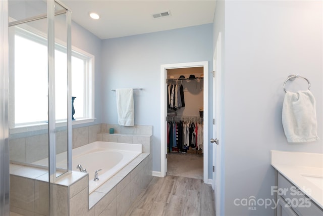 bathroom with vanity, visible vents, a shower stall, a walk in closet, and a bath