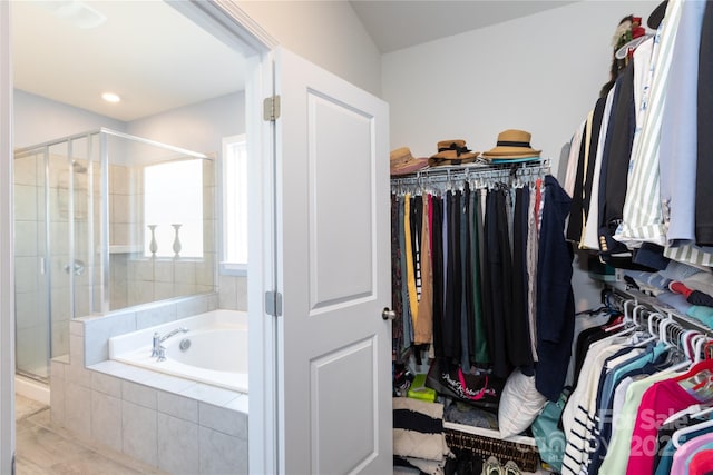 interior space featuring a shower stall, a spacious closet, a garden tub, and tile patterned floors