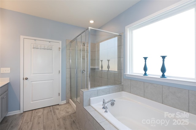 bathroom with vanity, a garden tub, wood finished floors, and a stall shower