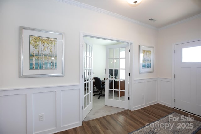 entryway with visible vents, crown molding, a wainscoted wall, french doors, and wood finished floors