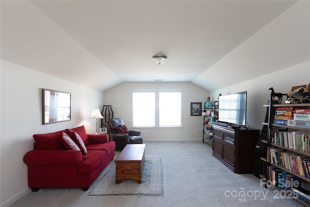 living area with baseboards, light carpet, and vaulted ceiling