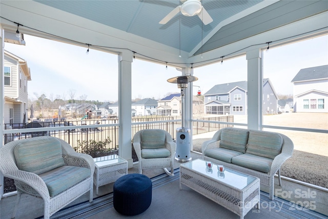 sunroom / solarium featuring a residential view, lofted ceiling, and a ceiling fan