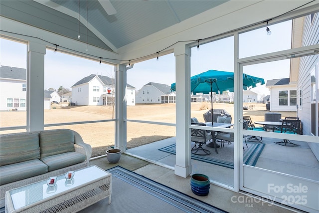 sunroom with a residential view, a healthy amount of sunlight, and vaulted ceiling