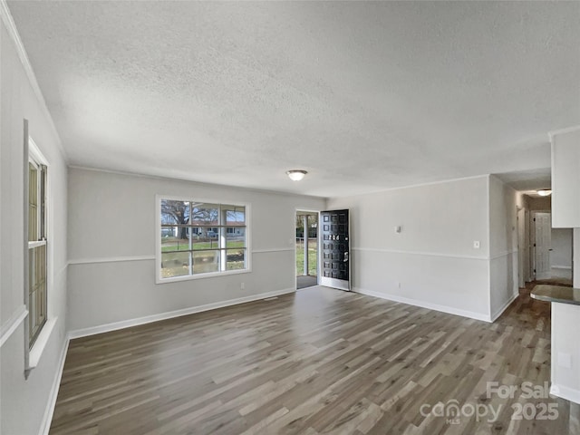 unfurnished living room with baseboards, a textured ceiling, and wood finished floors